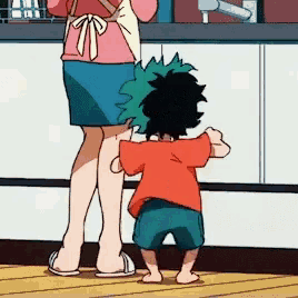 a woman and a little boy are standing in a kitchen .