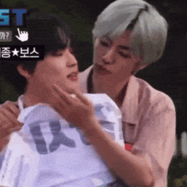 a man is holding another man 's neck while they are standing next to each other in a park .