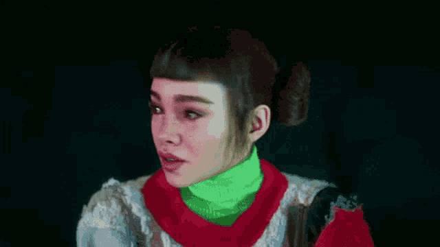 a woman with freckles is wearing a green turtleneck and a red scarf