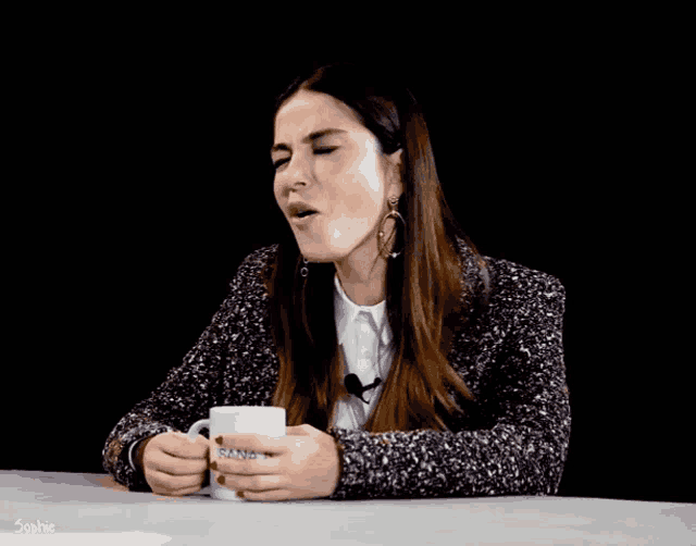 a woman is sitting at a table holding a mug that says sophie
