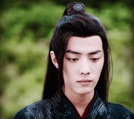 a man with long hair is wearing a ponytail and a ring on his head