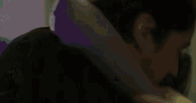 a man is laying down with a purple pillow on his neck