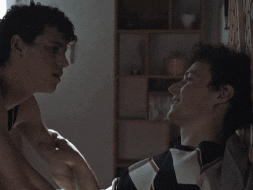 two men are kissing in a dark room
