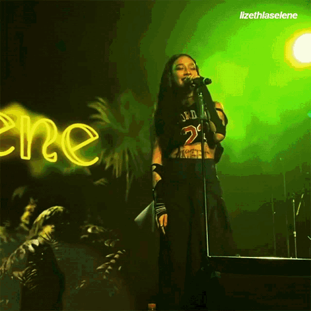 a woman singing into a microphone in front of a neon sign that says ere