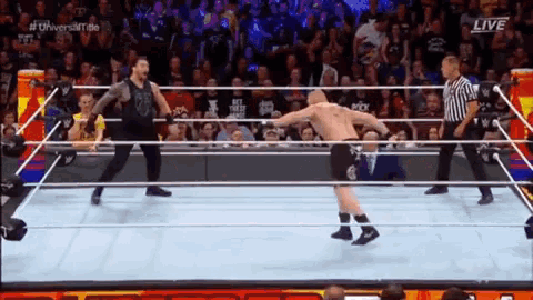 two men are wrestling in a wrestling ring with a referee watching .