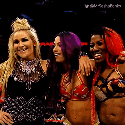 three female wrestlers are posing for a picture together and smiling for the camera .