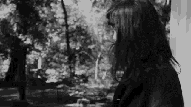 a black and white photo of a woman standing in front of a window .