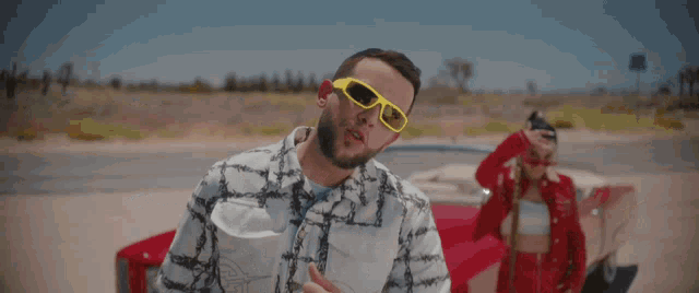 a man wearing yellow sunglasses stands next to another man