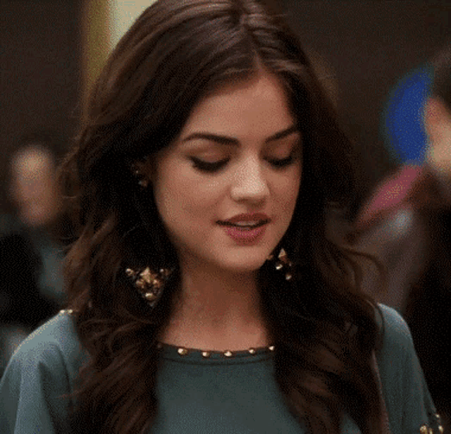 a close up of a woman 's face wearing earrings and a green top .
