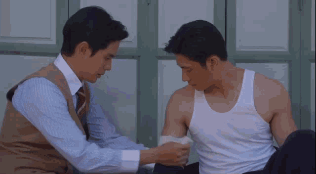two men are sitting next to each other and one of them has a bandage on his arm