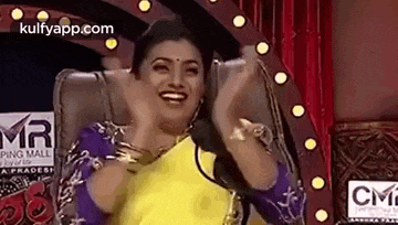 a woman is sitting in a chair with her hands in the air while laughing .