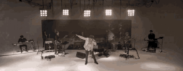 a man singing into a microphone while a band plays behind him