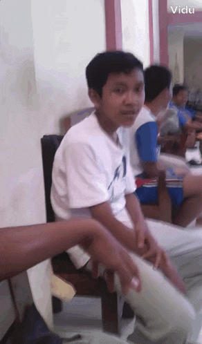 a boy in a white shirt with the number 1 on it is sitting in a chair