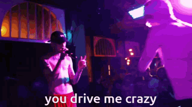 a man singing into a microphone with the words you drive me crazy on the bottom