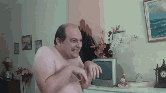 a man without a shirt is standing in front of a television in a living room
