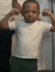a young boy is flexing his muscles while standing next to a woman .