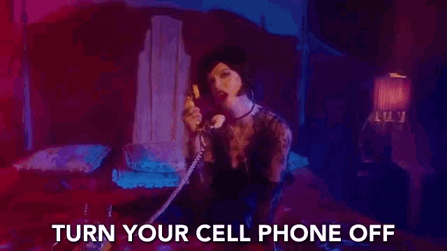 a woman is sitting on a bed talking on a telephone and the words `` turn your cell phone off '' are displayed .