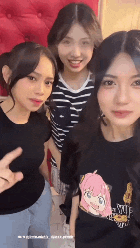 three girls are posing for a picture and one of them is wearing a shirt that says yuj