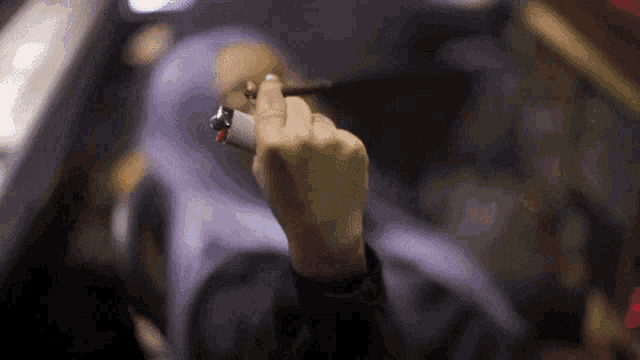 a person is holding a lighter and a cigar in their hand