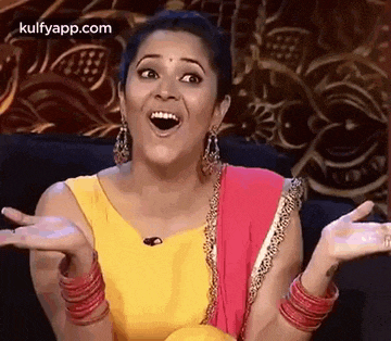 a woman is sitting on a couch with her mouth open and arms outstretched .