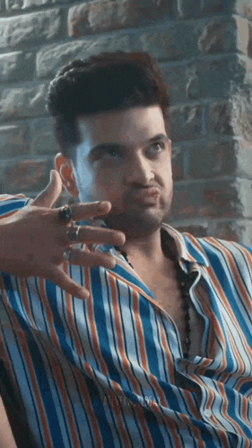 the man is wearing a striped shirt and a ring on his finger .