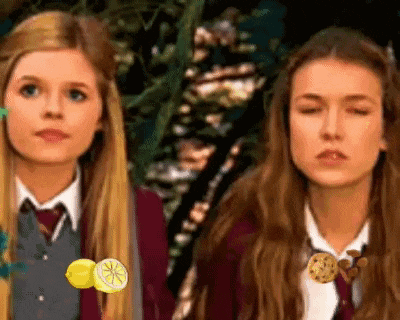 two girls are standing next to each other with one holding a lemon
