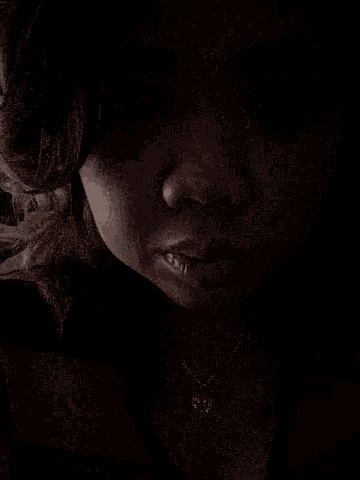 a close up of a woman 's face in a dark room with her eyes closed .