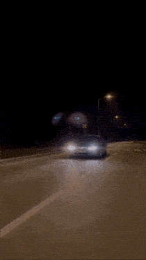 a white car is driving down a street at night with a license plate that says tk - 88