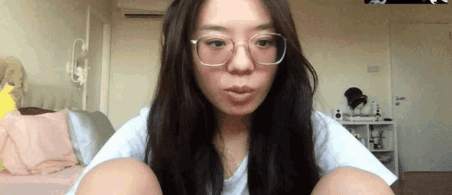 a woman wearing glasses and a white shirt is sitting on a couch