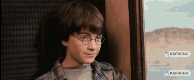 a young boy wearing glasses is looking out of a window with kapwing written on the bottom