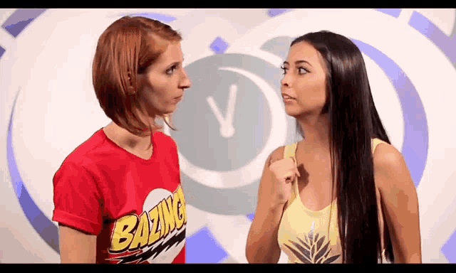 a woman wearing a red shirt that says bazinga looks at another woman