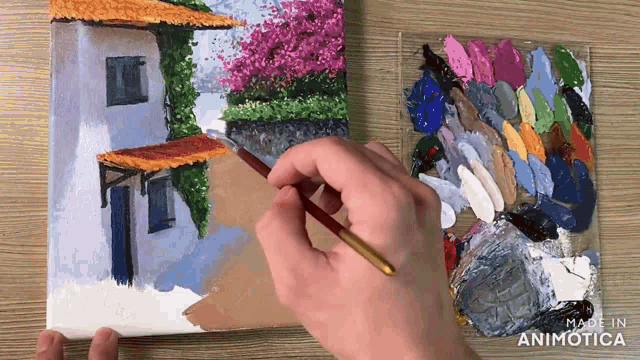 a person is painting a picture of a house with a palette of paint in the background