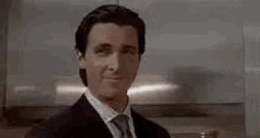 a man in a suit and tie is standing in front of a refrigerator in a kitchen .