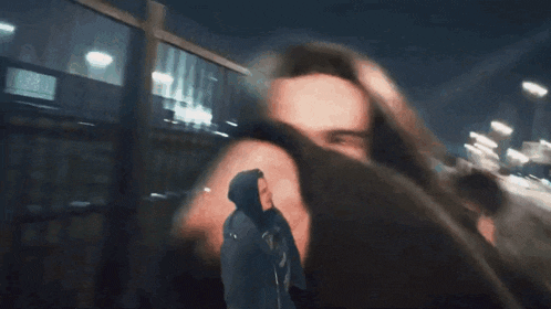 a man in a hooded jacket is walking down the street at night