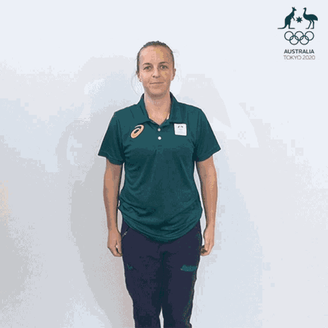 a woman in a green polo shirt stands in front of a sign that says australia