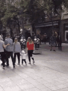 a group of people are walking down a brick sidewalk