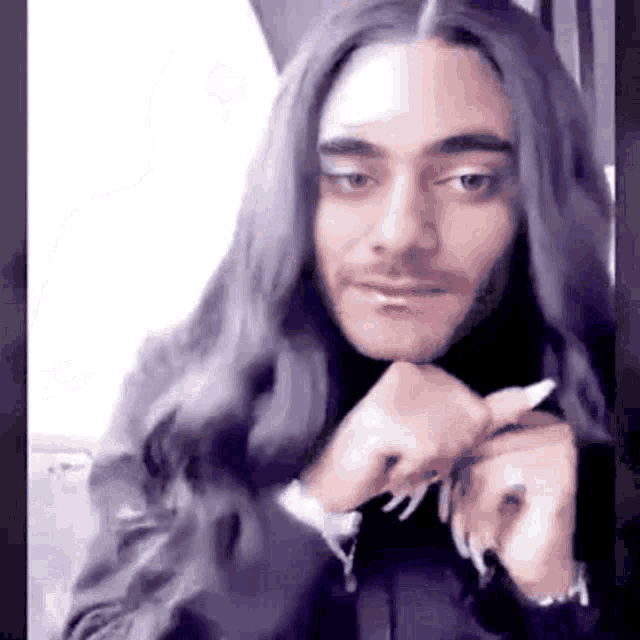 a man with long black hair and a beard is wearing a wig .