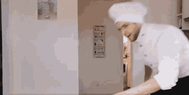 a man in a chef 's hat is standing in front of a sign that says " smile "