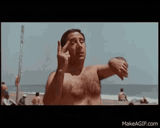 a shirtless man is standing on a beach with his arms outstretched .