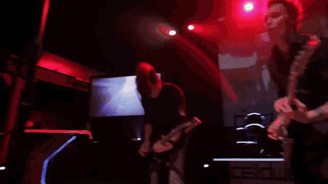 a man is singing into a microphone in a dark room with red lights .