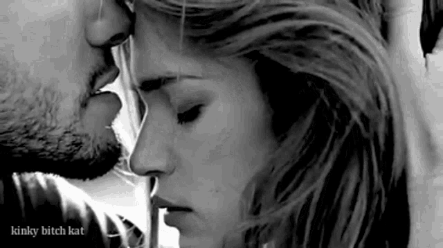 a black and white photo of a man and woman kissing .