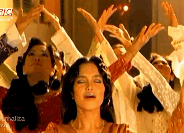 a group of women are dancing in front of a sign that says " rc "