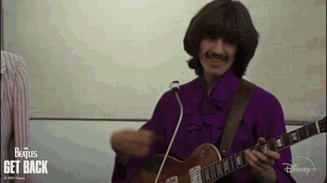 a man in a purple shirt is playing a guitar with the beatles get back written on the bottom right