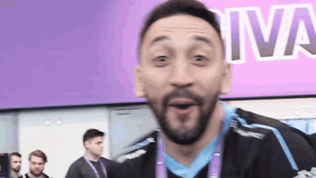 a man with a beard is making a funny face in front of a large purple sign .