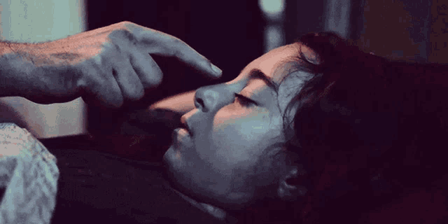 a man is touching a woman 's forehead while she sleeps