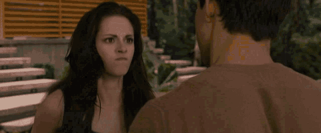 a woman is holding a man 's arm in a forest in a close up .