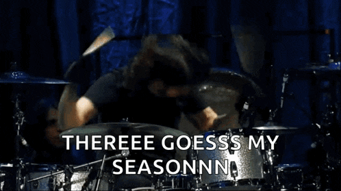 a man is playing drums on a stage with the words `` there goes my season '' written above him .