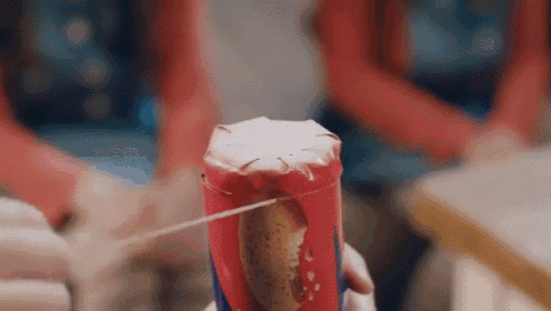 a close up of a person holding a can of soda with a string through it .