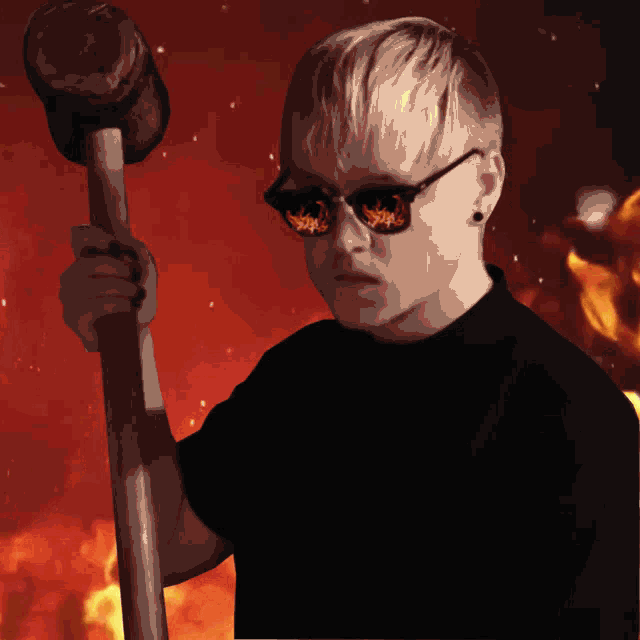 a man wearing sunglasses and a black shirt is holding a large wooden hammer