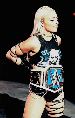 a female wrestler is wearing a black top with a picture of a woman and the letter w on it